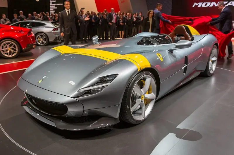 Szary Ferrari Monza SP1 z żółtymi pasami, odsłaniany na scenie.