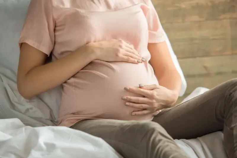 Kobieta w ciąży z dłońmi na brzuchu, martwiąca się o niskie erytrocyty w ciąży.