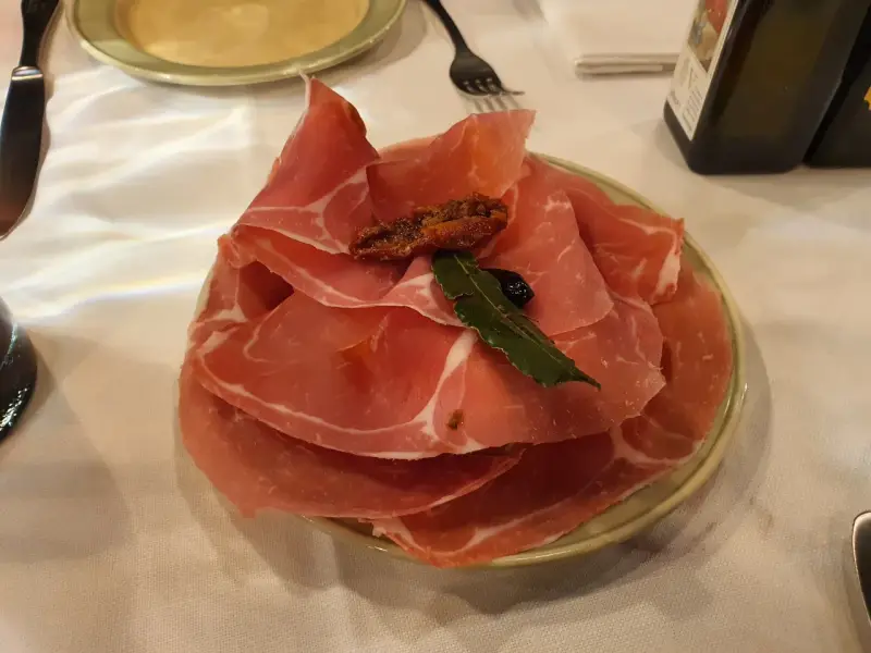 Plastry prosciutto na talerzu, idealne na przystawkę we Florencji. Co zjeść? Prosciutto to świetny wybór!