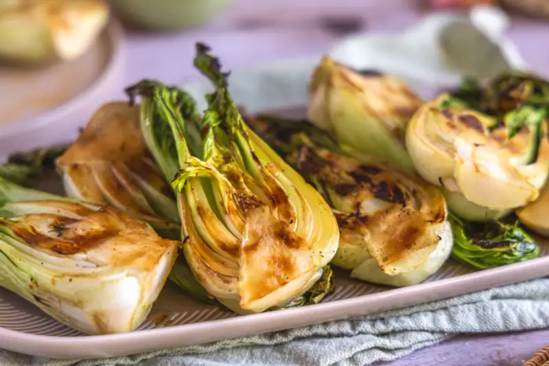 Halbierte Pak Choi-Stücke, die auf einem Teller mit Grillspuren liegen. Köstlich und gesund!