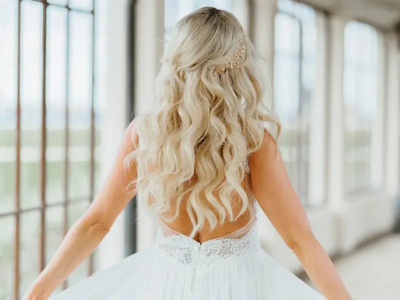 Długie, falowane blond włosy ozdobione złotą spinką. Fryzura w stylu lat 20. idealna na ślub.