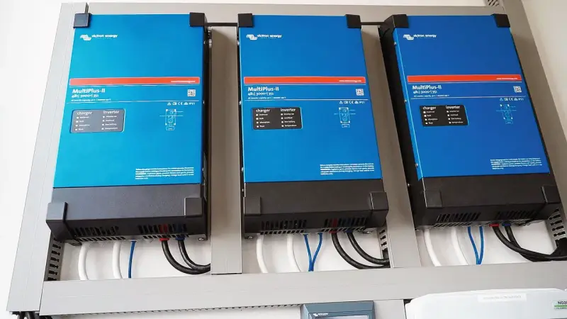 Trzy niebieskie falowniki Victron Energy MultiPlus-II zamontowane obok siebie. Od września 2026 r. każdy blok musi posiadać certyfikowany magazyn energii.