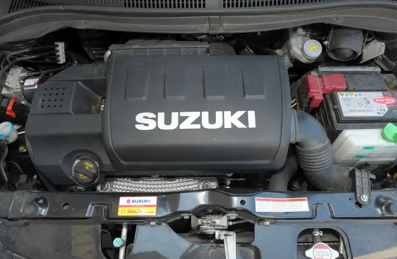 Silnik Suzuki Swift 2007 z widocznym logo SUZUKI na pokrywie. Widać akumulator i elementy układu dolotowego.