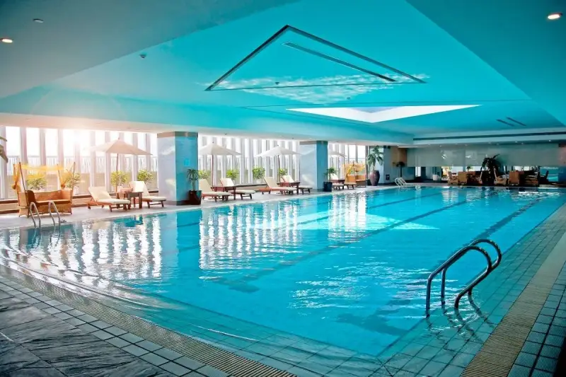 Relaks w hotelu z basenem na Podlasiu. Długi, błękitny basen z leżakami i parasolami, idealny na wakacje.