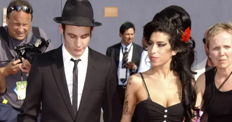 Blake Fielder-Civil w czarnym garniturze i kapeluszu obok Amy Winehouse z czerwoną różą we włosach.