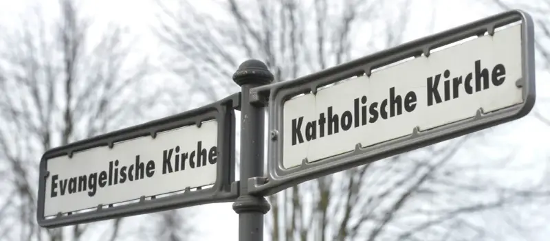 Straßenschilder weisen den Weg zur Evangelischen und Katholischen Kirche. Ein sichtbarer Unterschied katholisch evangelisch.