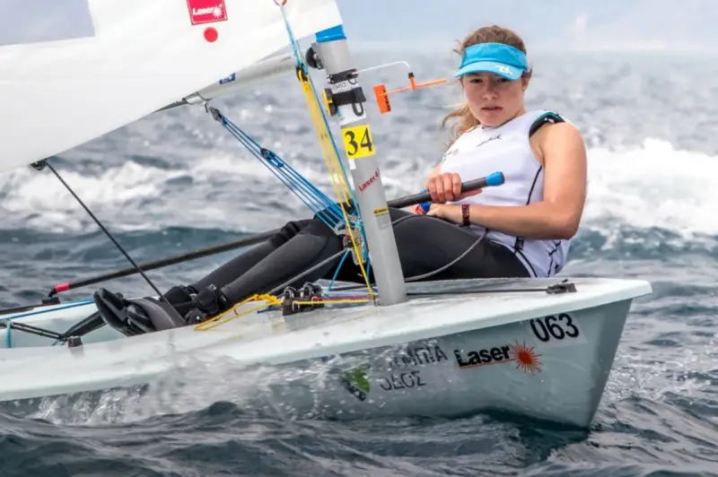 Jeune femme concentrée naviguant en deriveur solo, le bateau #063 fend les vagues.