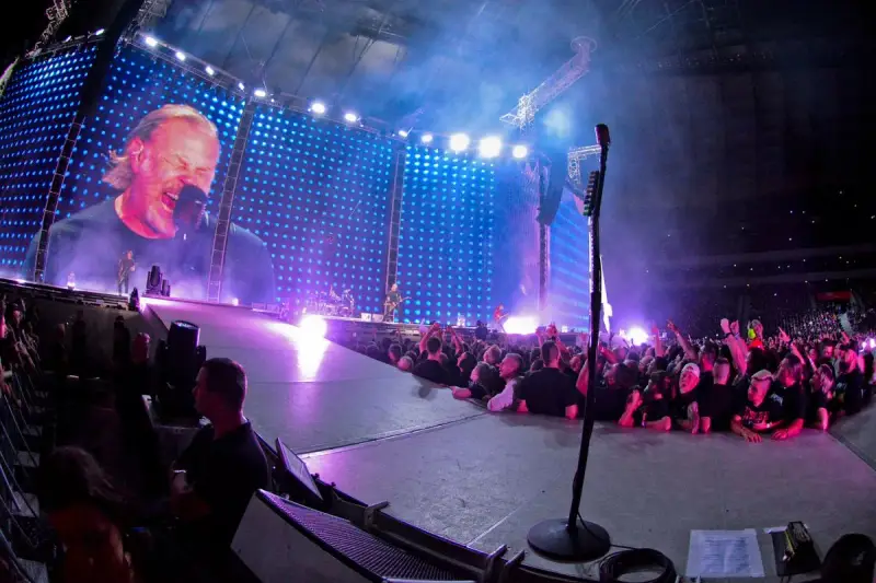 James Hetfield śpiewa na koncercie Metalliki w Warszawie. Tłum szaleje, a gigantyczny ekran pokazuje zbliżenie na wokalistę.