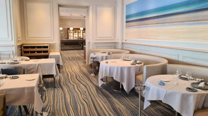 Élégant bistro à Saint-Malo, tables dressées, ambiance chic avec une fresque marine au mur.