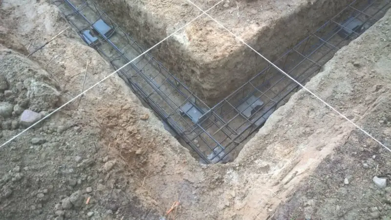 Zbrojenie fundamentów prefabrykowanych w wykopie. Stalowe pręty tworzą siatkę, gotową do zalania betonem.