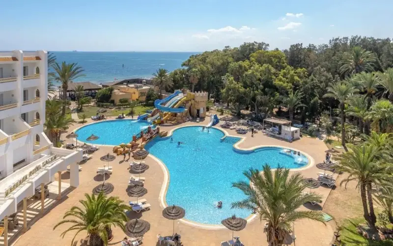 Hotel Marhaba Royal Salem kusi basenem z wodnymi zjeżdżalniami i palmami, w tle morze.
