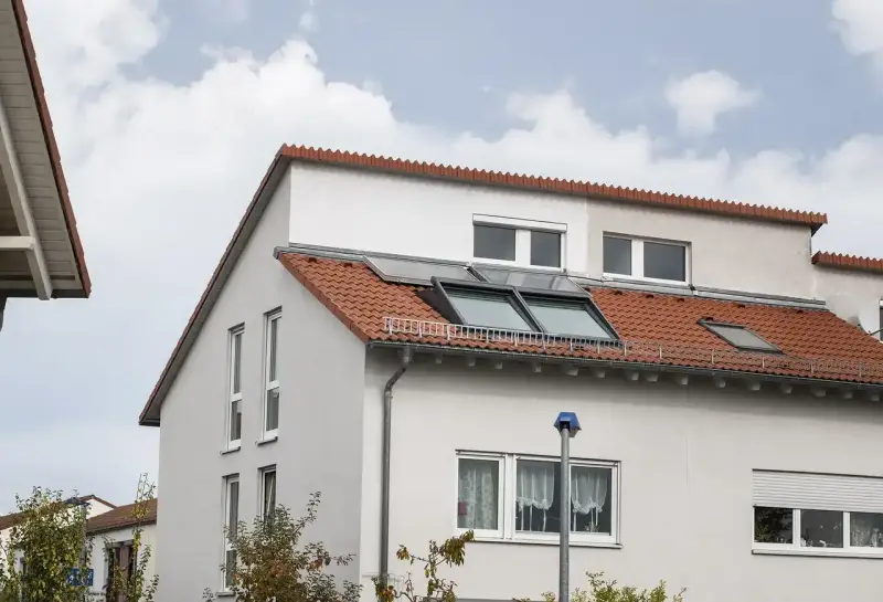 Ein Haus mit roten Ziegeln und Dachfenstern. Das Dach ist ein Pultdach, das nach einer Seite abfällt.