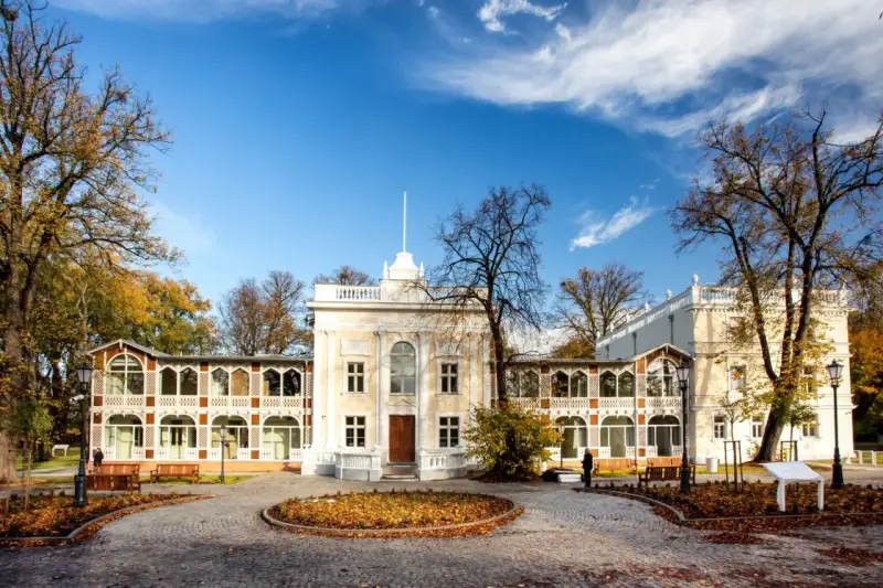 Brzeźno dom zdrojowy, zabytkowy budynek z arkadowymi werandami, otoczony jesiennym parkiem.