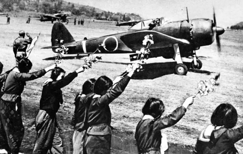 Des jeunes Japonais agitent des fleurs vers un avion, peut-être un adieu avant une mission kamikaze.