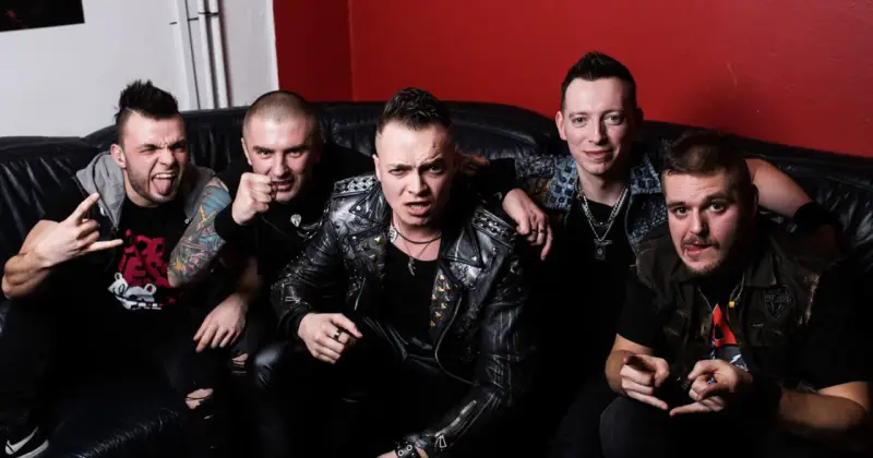 Pięciu mężczyzn w skórzanych kurtkach i z rockowymi fryzurami, jakby gotowi na nocny koncert. Wyglądają jak zespół nocny kochanek.