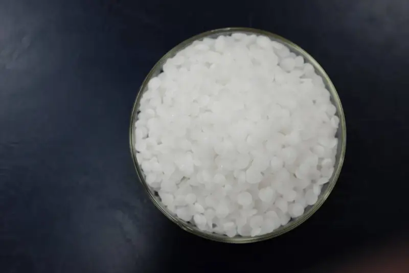 Schale mit weißen Pellets, die Natriumhydroxid darstellen.