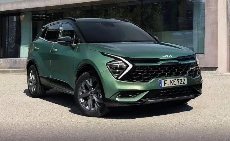 Nowy zielony Kia Sportage 1.6 benzyna z nowoczesnym designem, zaparkowany przed budynkiem.