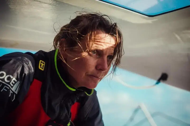 Anne Claire Le Berre, concentrée, le regard intense, le visage marqué par le soleil et le vent, sur un bateau.