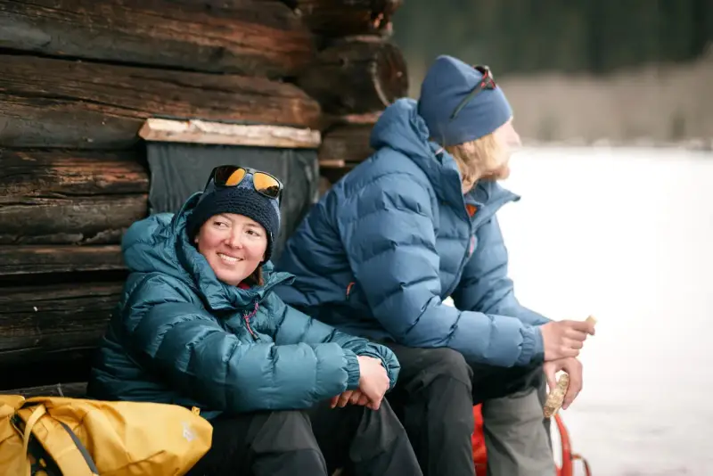 Zwei Personen in warmen 700 cuin Daunenjacken genießen eine Pause im Freien. Die Jacken halten sie bei kühler Temperatur angenehm warm.