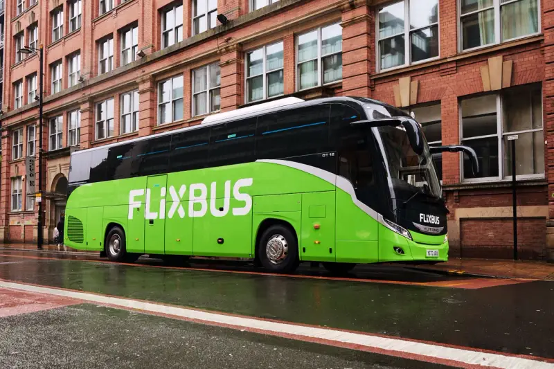 Zielony autokar FlixBus na mokrej ulicy. Wiele osób chwali sobie podróże tymi autobusami, a flixbus opinie są zazwyczaj pozytywne.