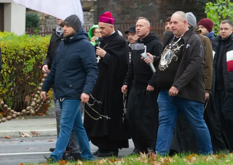 Grupa mężczyzn, w tym biskup, idzie ulicą. Niektórzy niosą różańce, jak rycerze Maryi.