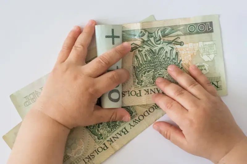 Dziecko bawi się banknotami 100 zł. Czy to już 12 tys na dziecko?