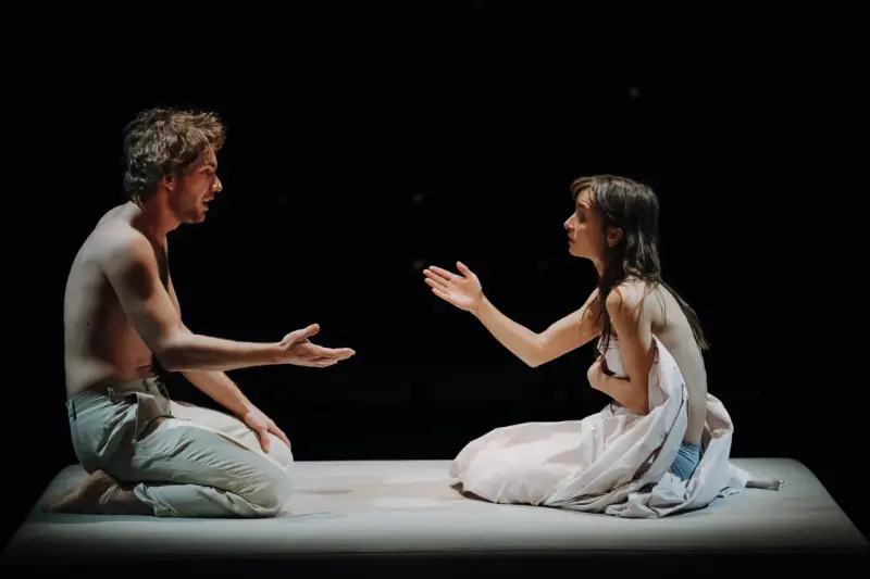 Aktorzy na scenie Teatru Narodowego, w intymnym geście, jakby dzielili się ostatnim tchnieniem.
