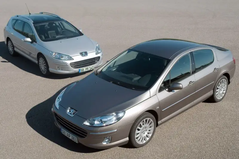 Dwa samochody Peugeot 407, sedan i kombi, na drodze. Wiele osób chwali sobie te modele, a opinie o Peugeot 407 są zazwyczaj pozytywne.