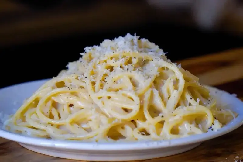 Pyszne cacio e pepe, czyli spaghetti z serem i pieprzem, posypane startym parmezanem.