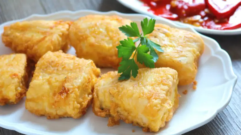 Crujientes trozos de merluza a la romana, dorados y listos para disfrutar. Un clásico plato español.