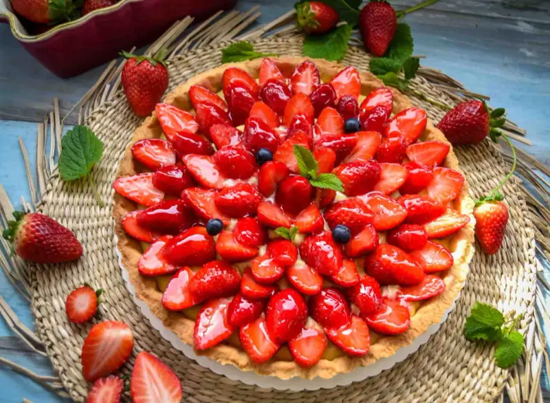 Ein leckerer Erdbeerkuchen mit einem wunderschönen Muster aus frischen Erdbeeren und Blaubeeren, glasiert und garniert mit Minze.