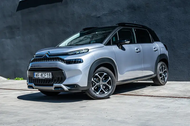 Srebrny Citroen C3 Aircross na tle ciemnej ściany. Wiele osób szuka **Citroen C3 Aircross opinie** przed zakupem.