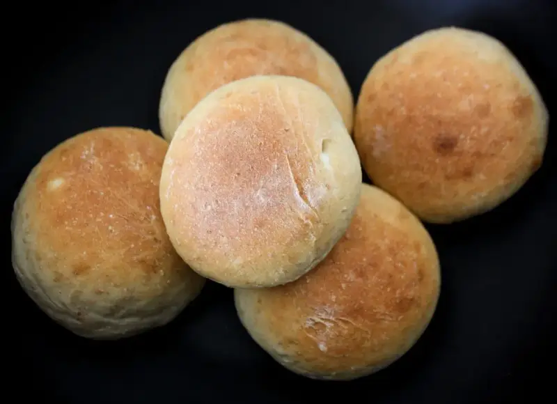 Fem nybakade frallor på en svart bakgrund. Perfekt för ett enkelt frallor recept.