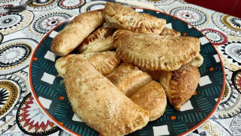 Plato lleno de empanadillas de cabello de ángel, doradas y espolvoreadas con semillas de sésamo.