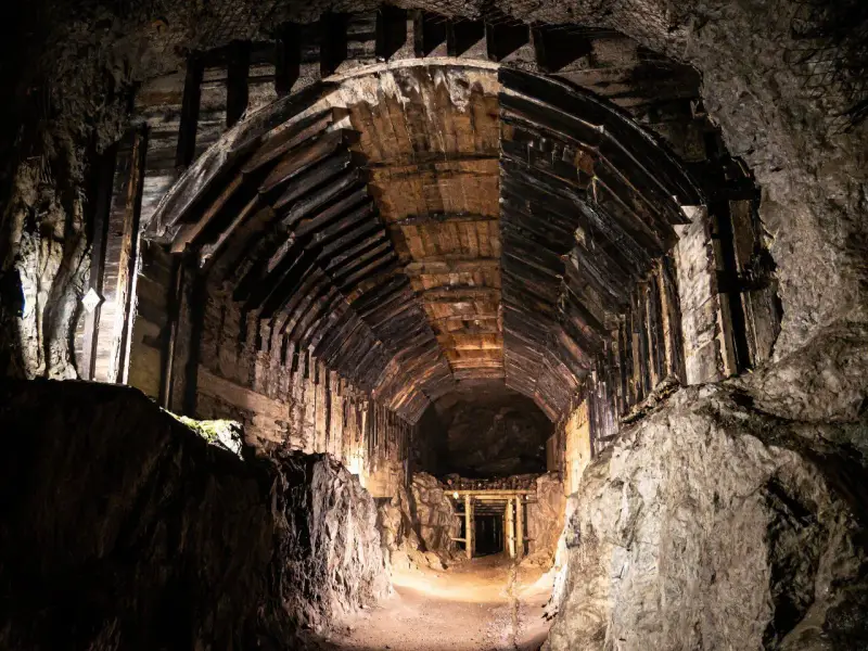 Wnętrze tunelu w kompleksie Riese, gdzie kryją się tajemnice wojny. Drewniane wsporniki i skalne ściany tworzą mroczny korytarz.