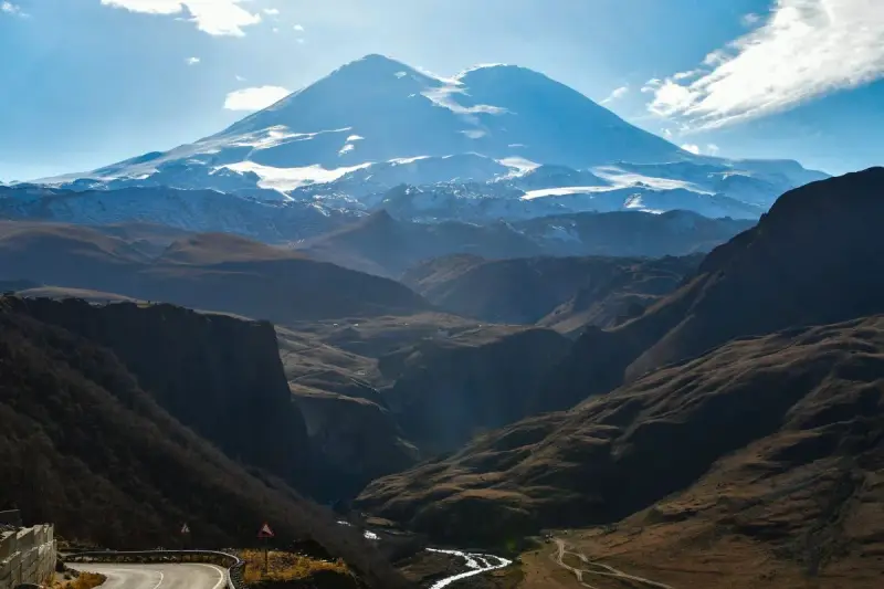 Majestatyczny Elbrus, najwyższy szczyt Europy, góruje nad doliną. Kręta droga prowadzi przez malownicze góry.