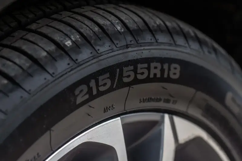 Zbliżenie na oponę z oznaczeniem 215/55R18. Widoczne oznaczenie M+S potwierdza, że jest to oznaczenie opon wielosezonowych, gotowych na każdą pogodę.