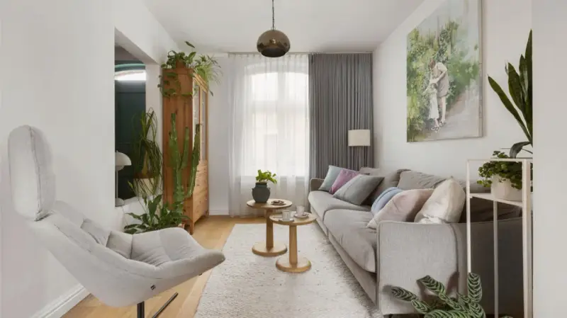 Przytulny salon w domu z szarą kanapą, wygodnym fotelem i mnóstwem zielonych roślin.