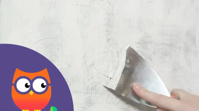 Maintenant, il faut enlever la peinture d'un mur avec une spatule. Un hibou curieux observe.