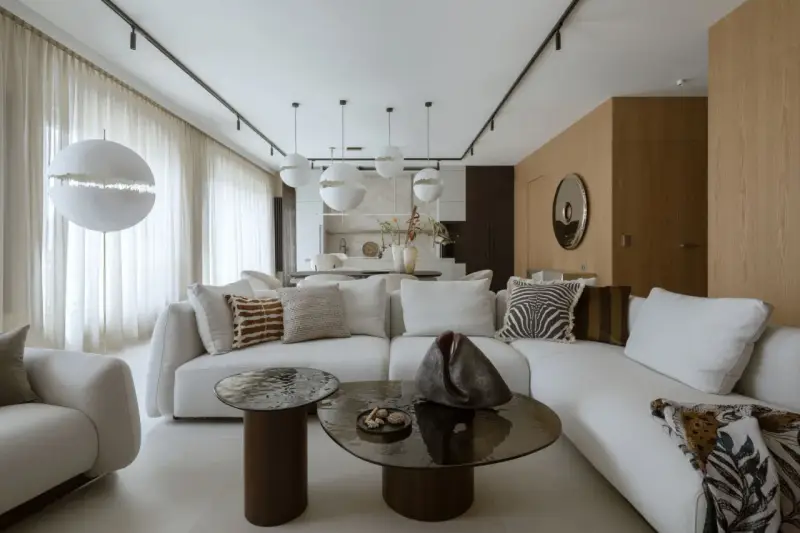 Nowoczesny projekt mieszkania z białą sofą, okrągłymi stolikami i designerskimi lampami.