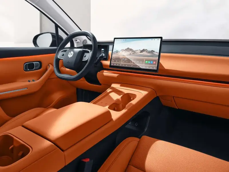Interni eleganti e moderni della Leapmotor C10, con sedili in pelle arancione, ampio display centrale e volante sportivo.