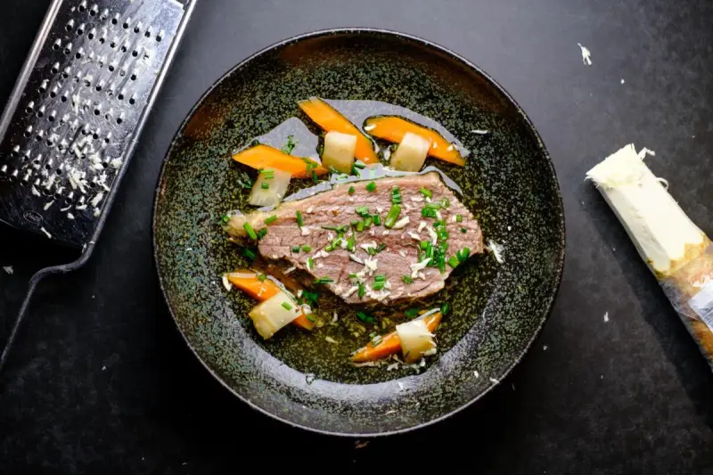 Zarter Tafelspitz braten im Topf, serviert mit Karotten und Lauch. Frisch geriebener Meerrettich daneben.