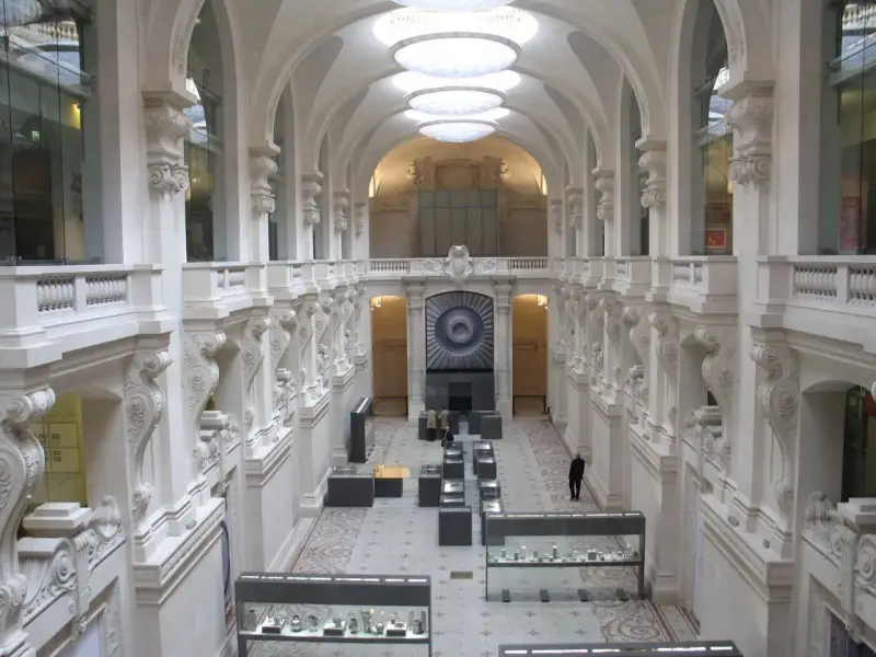 Interior del museo de artes decorativas, con arcos, balcones y vitrinas exhibiendo objetos.