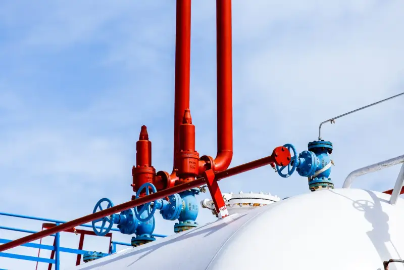 Zawory i rury przy białym zbiorniku na gaz. Zastanawiasz się, na ile wystarcza zbiornik na gaz 2700?