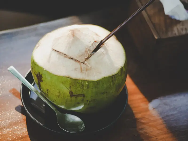 Une noix de coco fraîchement ouverte, prête à être dégustée. L'eau de coco, promesse d'une hydratation pure, est un délice qui ne trompe jamais.