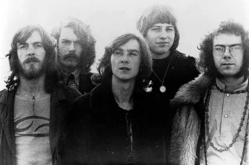 Cinq membres de King Crimson posent ensemble, arborant des coiffures et des vêtements typiques des années 70.