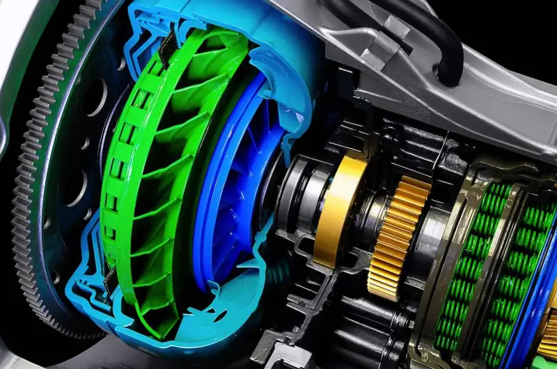 Corte detallado de una **caja de cambios automática** con turbina verde y azul, engranajes dorados y resortes verdes.