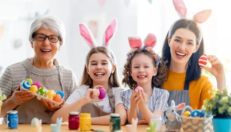 Familie feiert die Osterferien BW 2026 mit bunten Eiern und Hasenohren.