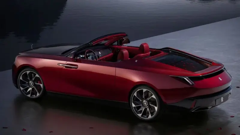 Czerwony kabriolet Rolls-Royce, najdroższe auto na świecie, lśni przy wodzie.