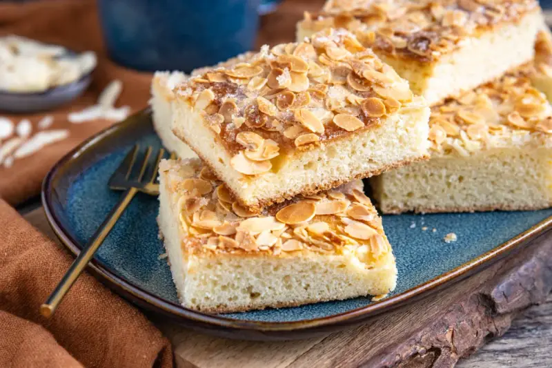 Original norddeutscher Butterkuchen mit Mandeln und Zucker bestreut, auf einem blauen Teller angerichtet.